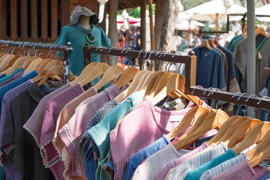 Clothes racks with cotton dresses on hangers. Showcase with clothes on local street local market.